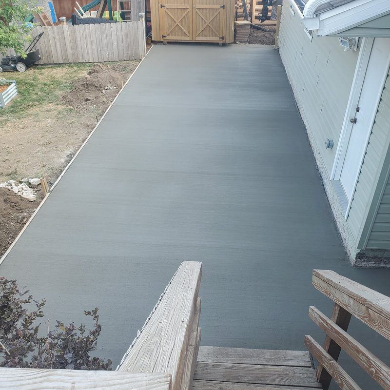 Freshly poured and finished concrete walkway beside a house